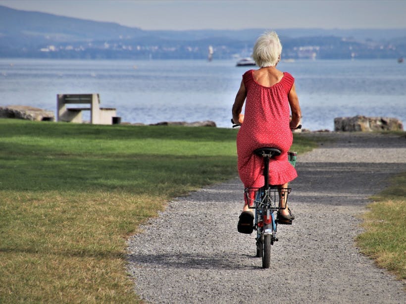 Äldre kvinna cyklar på grusväg
