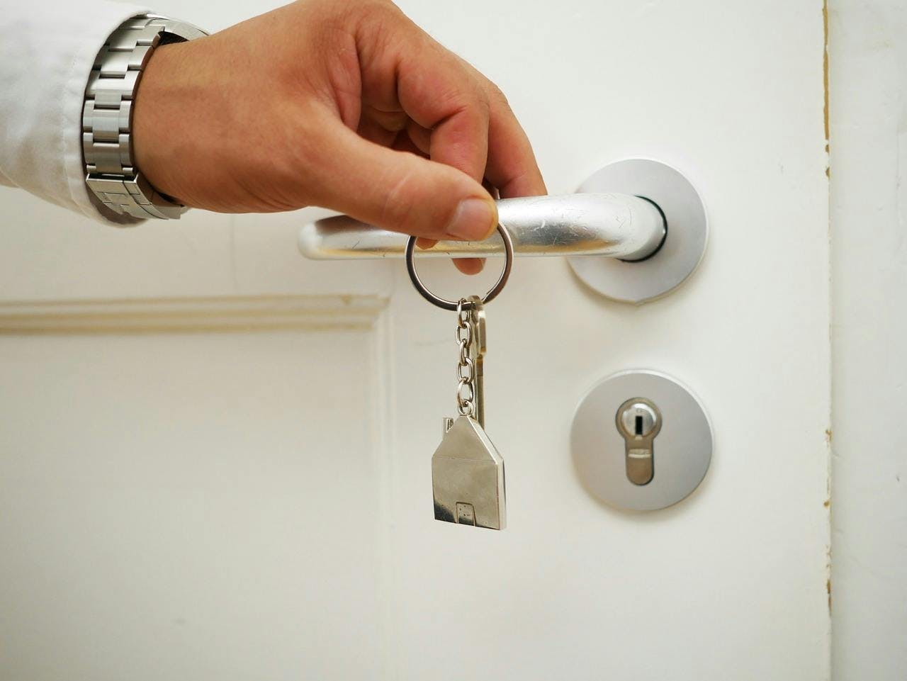 Hand med nycklar framför dörr